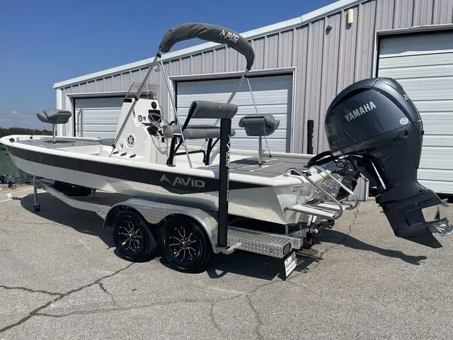 Slide: The Image of 2024 Avid 23 FSX boat with Yamaha engine on trailer, parked outside a garage. - 2
