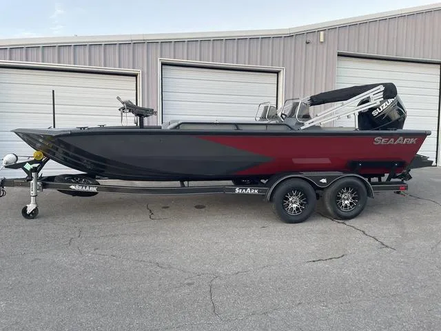 Slide: The Image of 2024 SeaArk Easy 200 boat with Suzuki engine on a trailer, parked outside a garage. - 1