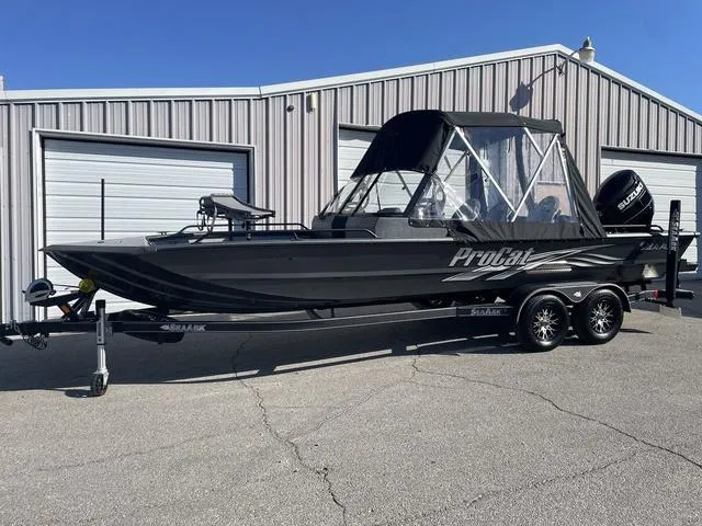 Slide: The Image of 2025 SeaArk Pro Cat 240 boat with canopy, parked on a trailer outside a garage. - 1