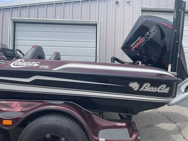 Slide: The Image of 2020 Bass Cat Cougar FTD boat with Mercury Pro XS engine, parked near a garage. - 2