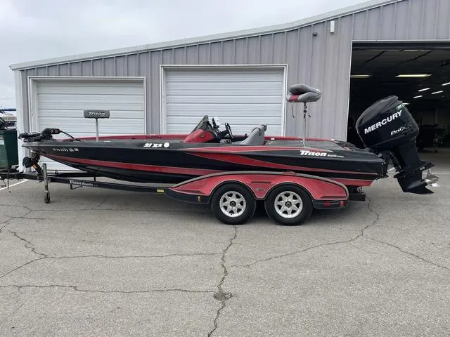 Slide: The Image of 2007 Triton 21 X2 bass boat with Mercury engine, parked outside a garage. - 1
