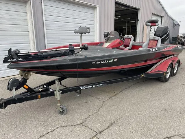 Slide: The Image of 2007 Triton 21 X2 boat on trailer, black and red, parked outside a garage. - 2