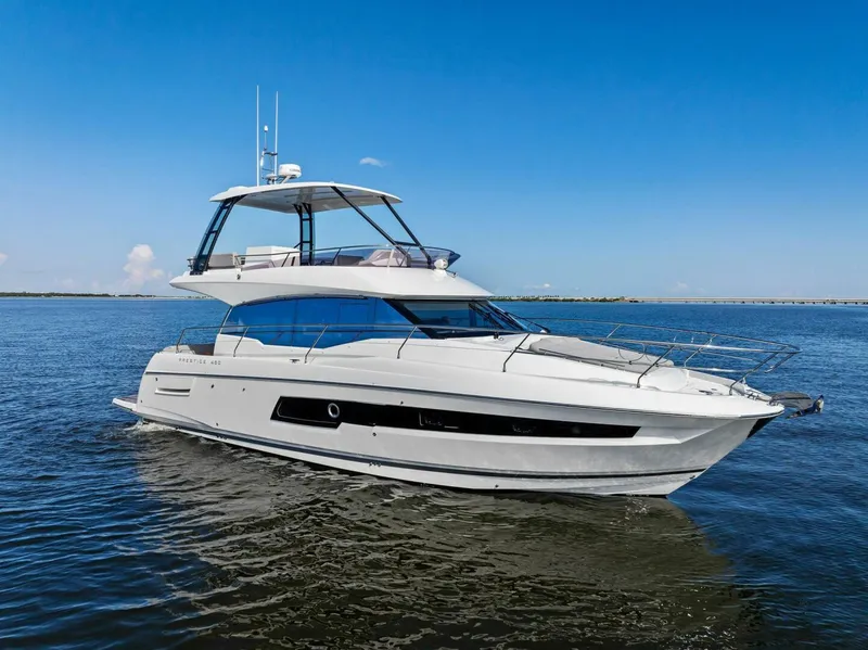 Slide: The Image of 2023 Prestige 460 Flybridge yacht on calm water under clear blue sky. - 1
