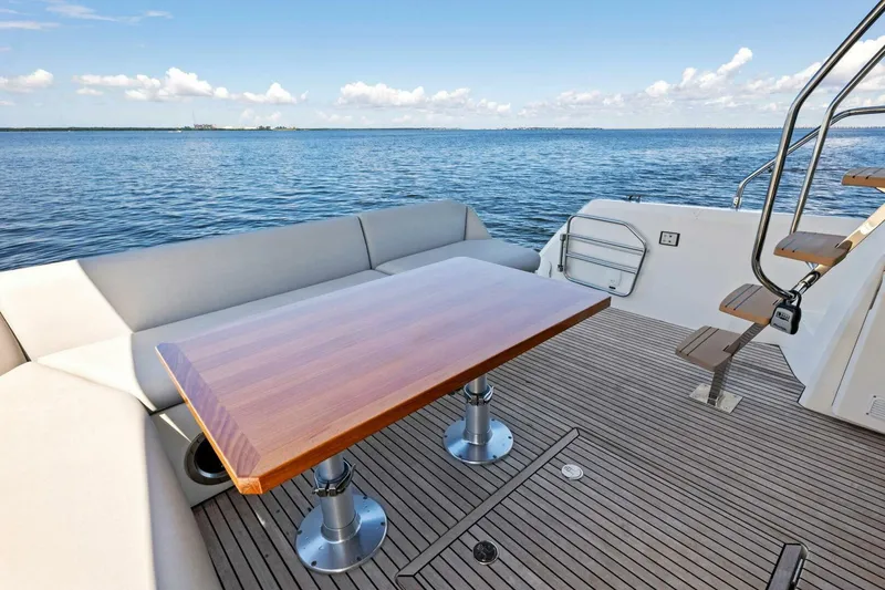 Slide: The Image of Prestige 460 Flybridge 2023 yacht deck with wooden table and ocean view. - 42