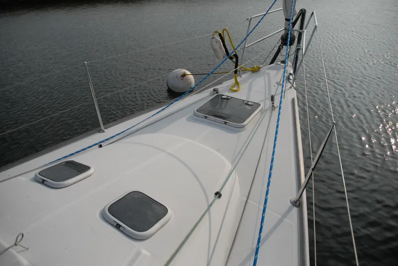 Slide: The Image of 2003 Beneteau 36.7 sailboat deck with hatches and rigging on calm water. - 11