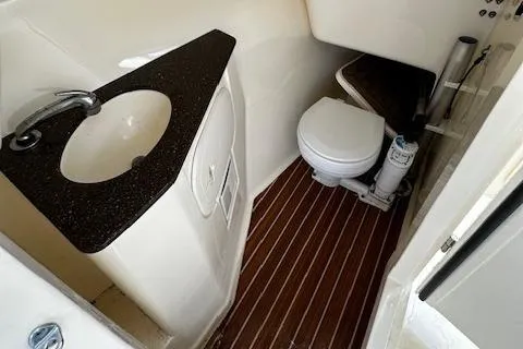 Slide: The Image of 2015 Scout 275 Dorado boat bathroom with sink and toilet, featuring wood-style flooring. - 13