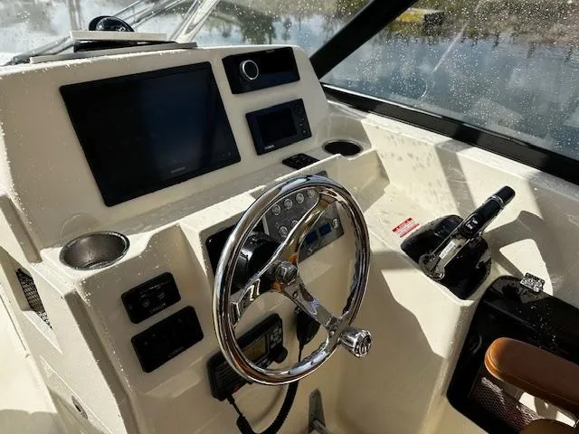 Slide: The Image of 2015 Scout 275 Dorado boat dashboard with steering wheel and navigation controls. - 4