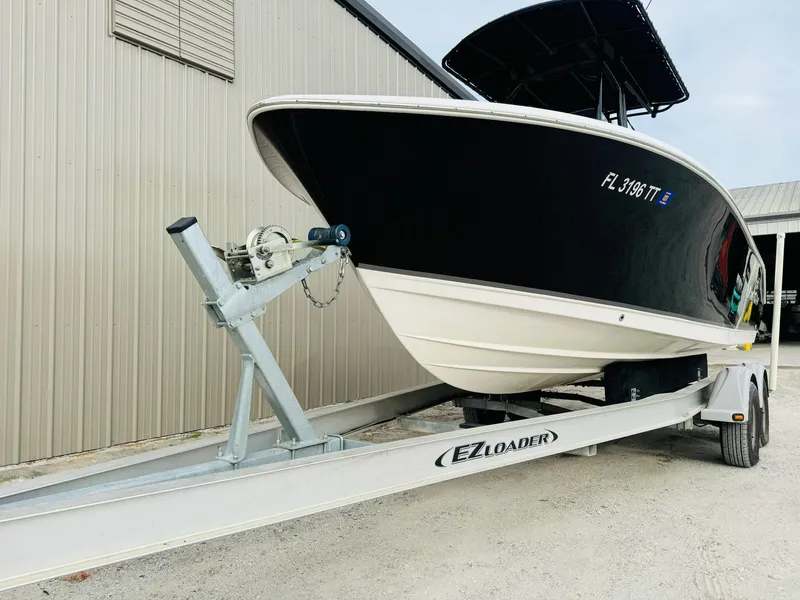 Slide: The Image of 2022 NauticStar 2102 Legacy boat on EZ Loader trailer, parked near a building. - 11