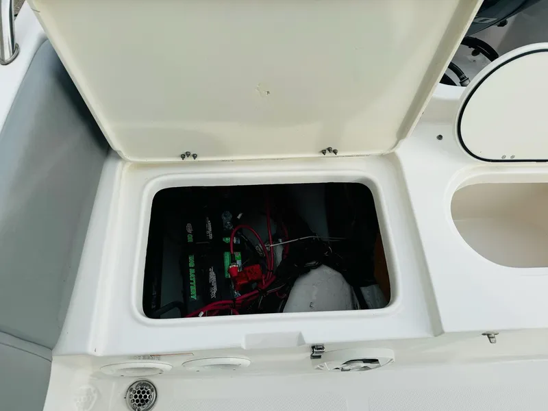 Slide: The Image of Open storage compartment on 2022 NauticStar 2102 Legacy boat, revealing battery and wiring. - 21