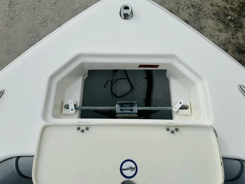 Slide: The Image of 2022 NauticStar 2102 Legacy boat anchor compartment, open lid, white deck. - 40
