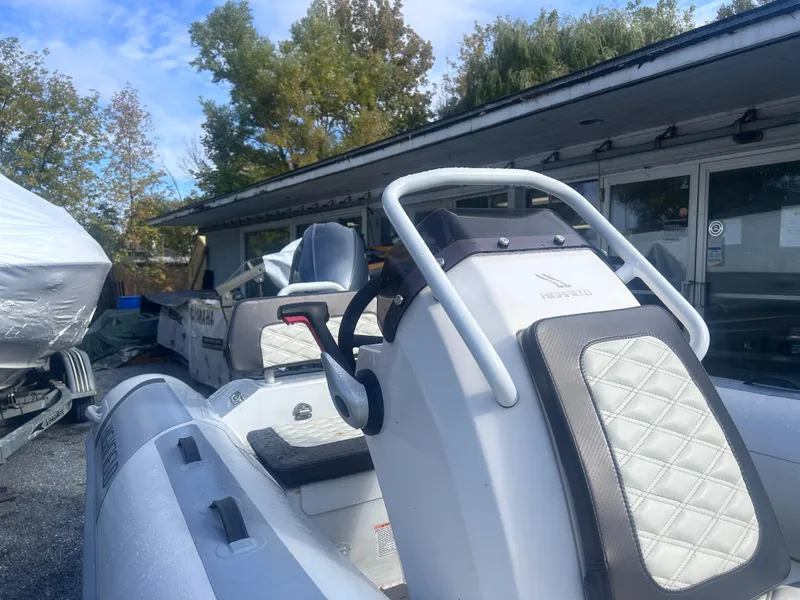 Slide: The Image of 2023 Highfield Sport 460 boat with white seating, parked outdoors near a building. - 7