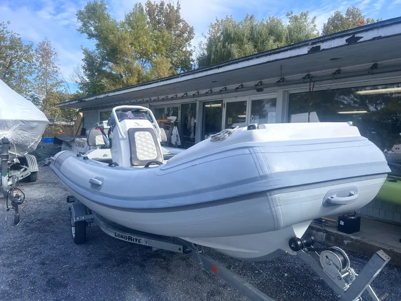 Slide: The Image of 2023 Highfield Sport 460 boat on trailer, parked outdoors near a building. - 8