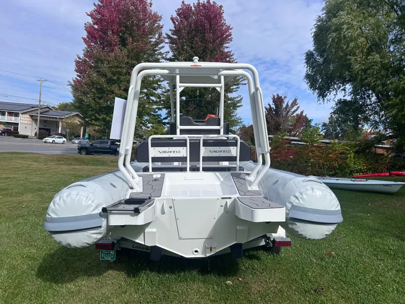 Slide: The Image of 2024 Highfield Sport 660 boat on grass, rear view, with trees in background. - 8