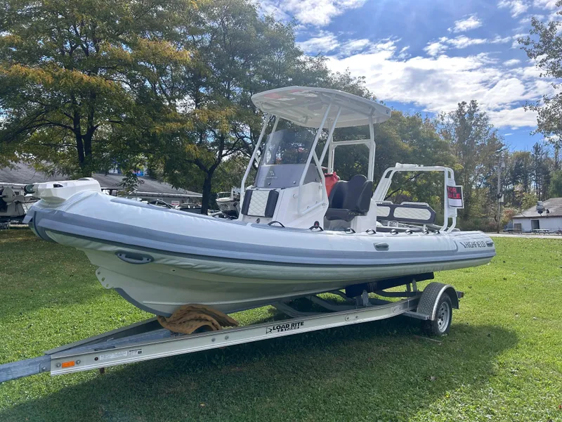 Slide: The Image of 2024 Highfield Sport 660 boat on trailer, parked on grass under a partly cloudy sky. - 9