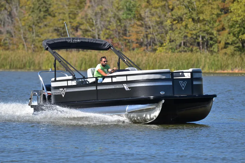 The Image of 2023 Viaggio DM18U pontoon boat cruising on a lake with lush greenery in the background. - 1