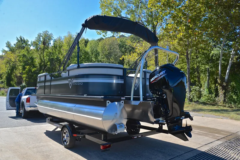 Slide: The Image of 2023 Viaggio DM18U pontoon boat with Mercury engine on trailer, surrounded by trees. - 11