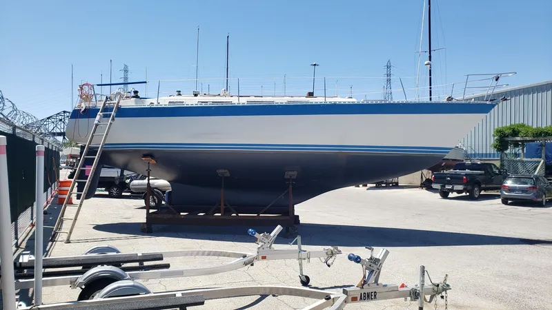 Slide: The Image of 1983 Wauquiez 38 MKI sailboat on dry dock, with trailers and vehicles nearby. - 2