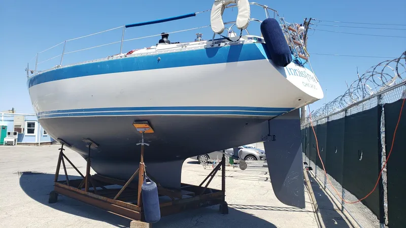 Slide: The Image of 1983 Wauquiez 38 MKI sailboat on dry dock, blue and white hull, sunny day. - 4