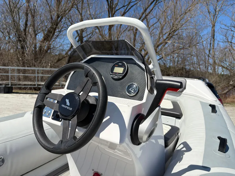 Slide: The Image of 2024 Highfield Sport 390 boat dashboard with steering wheel and controls, outdoors. - 10