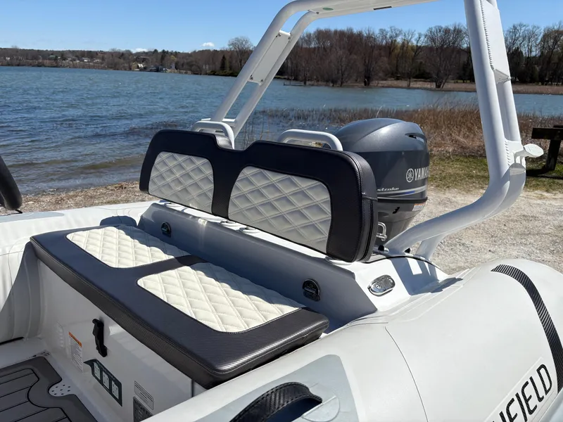 Slide: The Image of 2024 Highfield Sport 390 boat with Yamaha engine, featuring cushioned seating by a lake. - 12