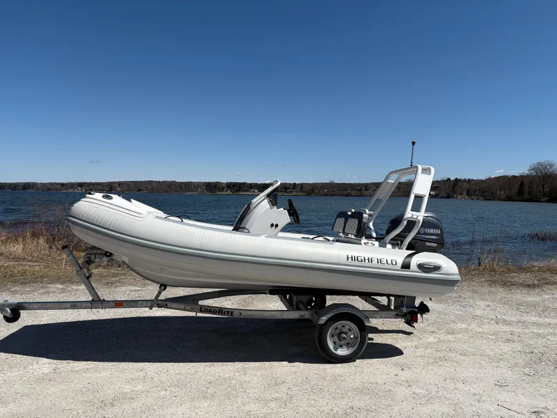 Slide: The Image of 2024 Highfield Sport 390 boat on trailer by a lake under clear blue sky. - 2