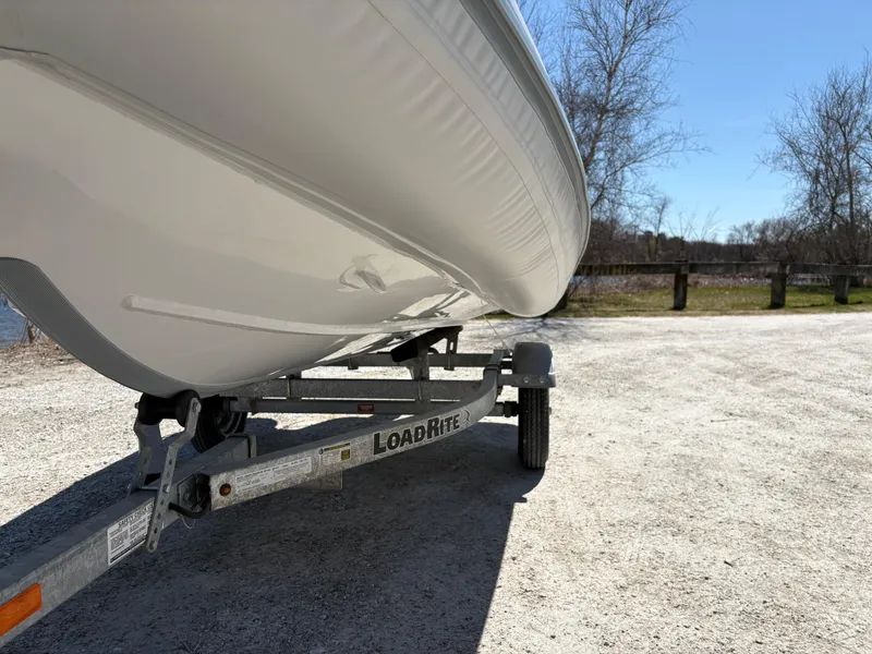Slide: The Image of 2024 Highfield Sport 390 boat on LoadRite trailer, parked outdoors on a sunny day. - 20