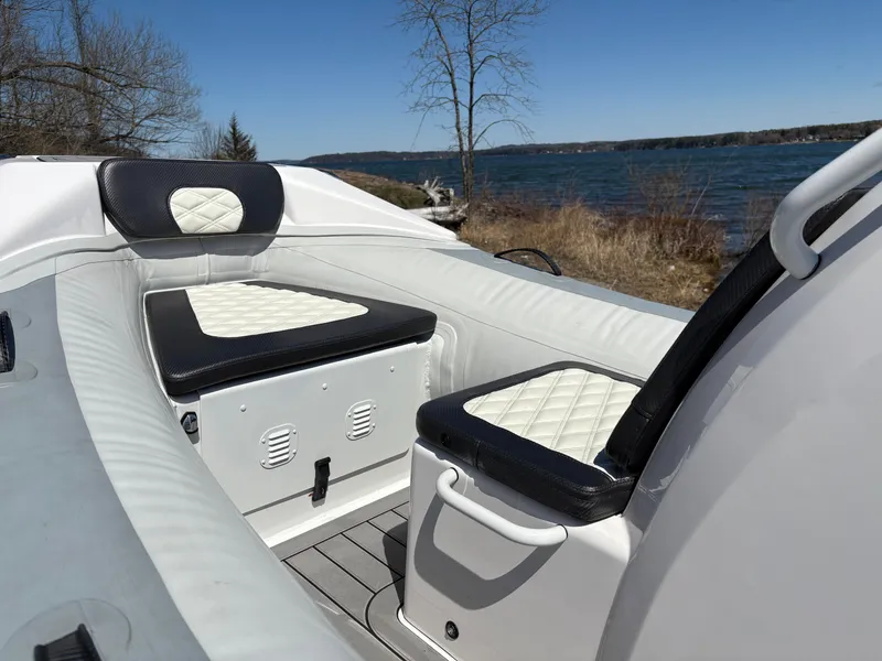 Slide: The Image of 2024 Highfield Sport 390 boat interior with cushioned seating by a lake. - 23