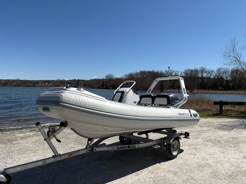 Slide: The Image of 2024 Highfield Sport 390 boat on trailer by a lake under clear blue sky. - 3