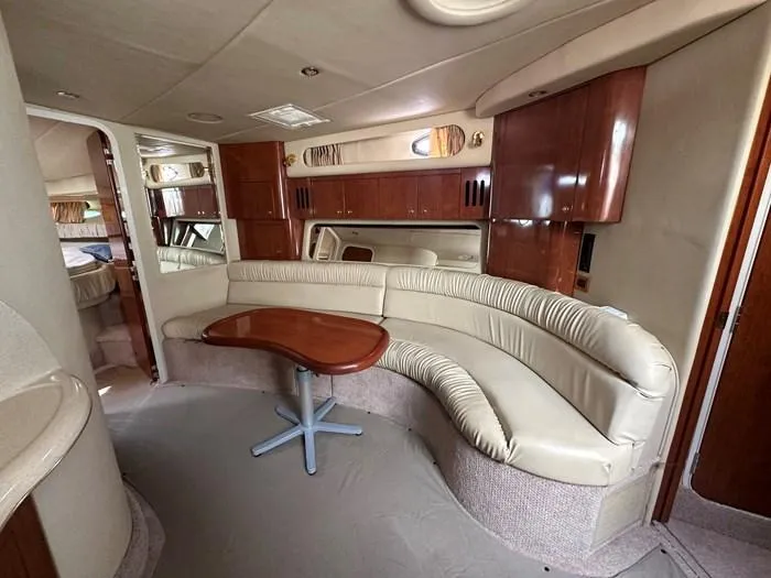 Slide: The Image of Luxurious interior of 2000 Sea Ray 410 Sundancer yacht with curved seating and wooden table. - 15