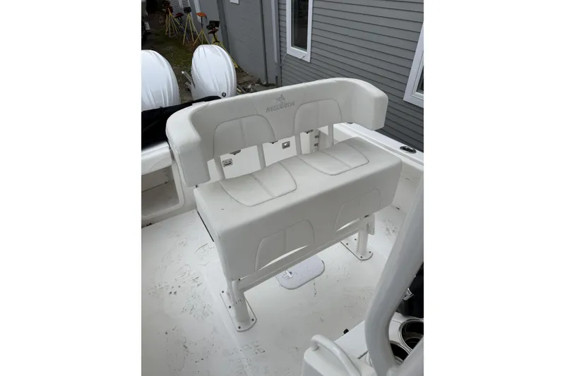 Slide: The Image of 2025 Regulator 23 boat seating with white cushioned bench and dual outboard motors. - 24