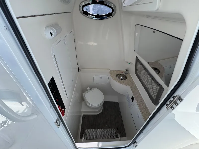 Slide: The Image of 2025 Regulator 28 boat interior with compact bathroom, featuring a toilet and sink. - 13