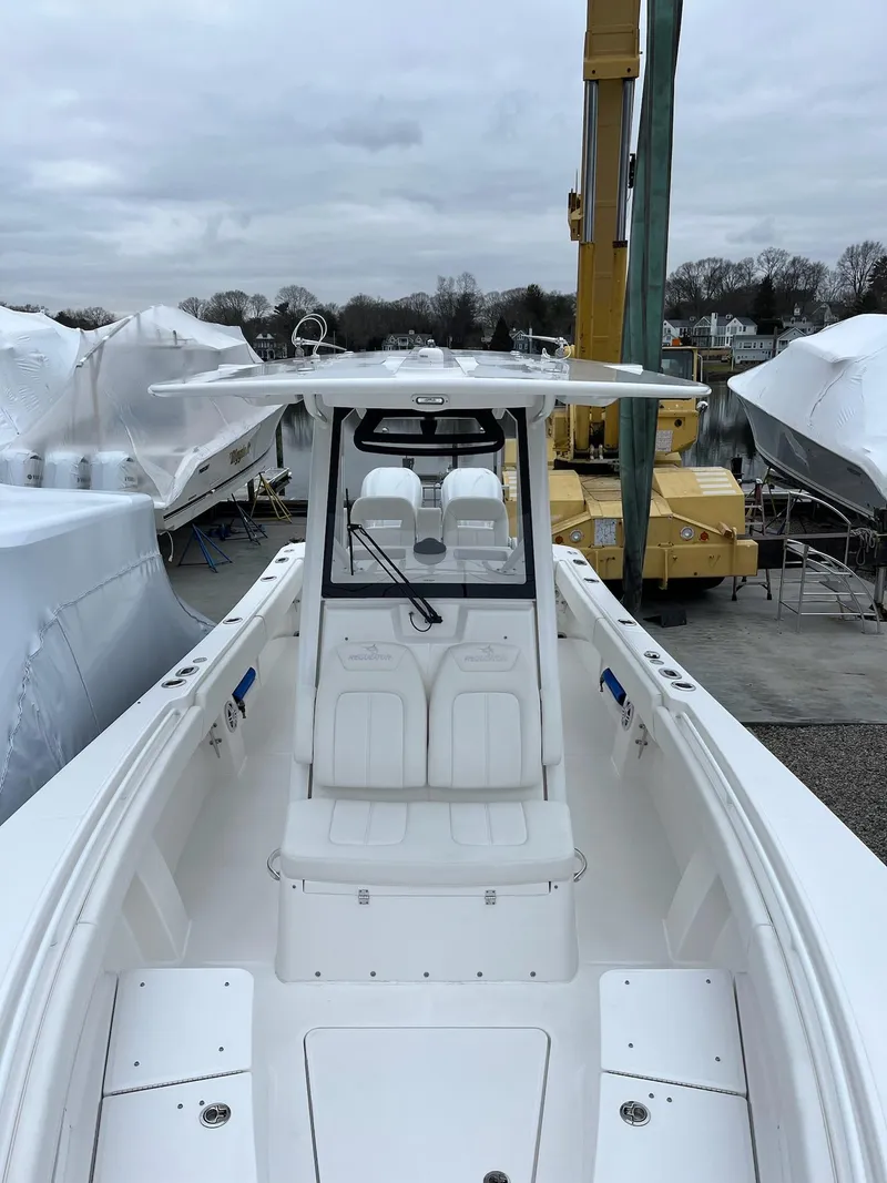 Slide: The Image of 2025 Regulator 28 boat, white exterior, docked with covered vessels in the background. - 18