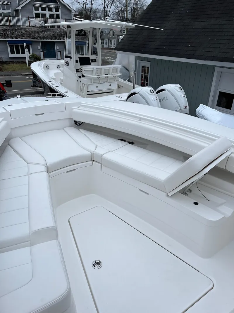 Slide: The Image of 2025 Regulator 28 boat with white seating and dual engines, docked near houses. - 32