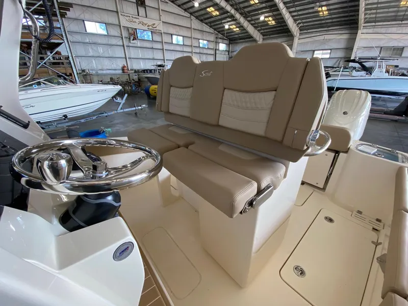 Slide: The Image of 2025 Scout 260 LXF boat interior with steering wheel and seating in a spacious warehouse. - 11
