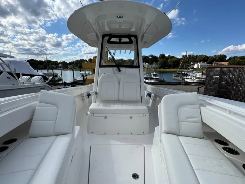 Slide: The Image of 2025 Regulator 31 boat interior with white seating, docked at a marina under a blue sky. - 19