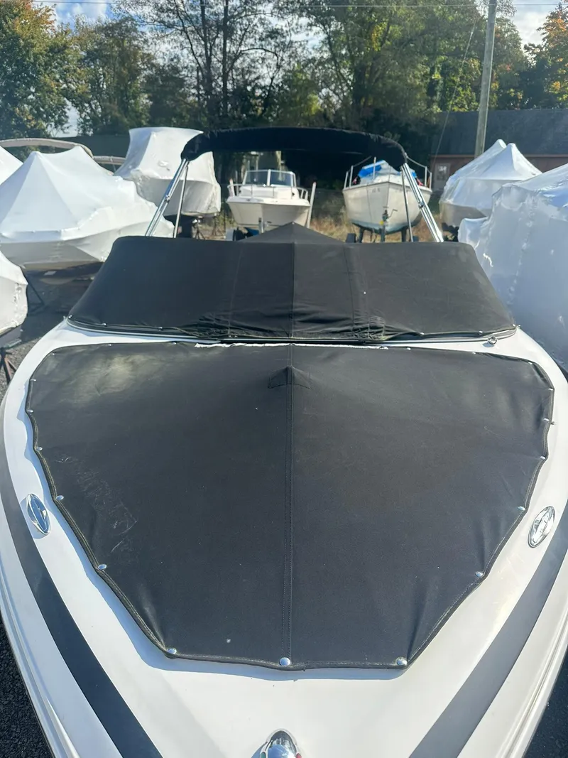 Slide: The Image of 2011 Regal 2100 Bowrider boat with black cover, parked outdoors. - 15