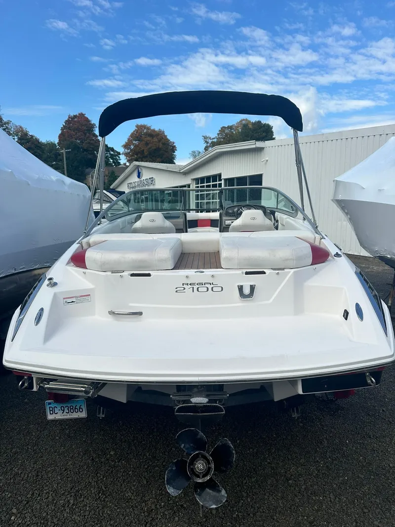 Slide: The Image of 2011 Regal 2100 Bowrider boat with white exterior, parked outdoors. - 3