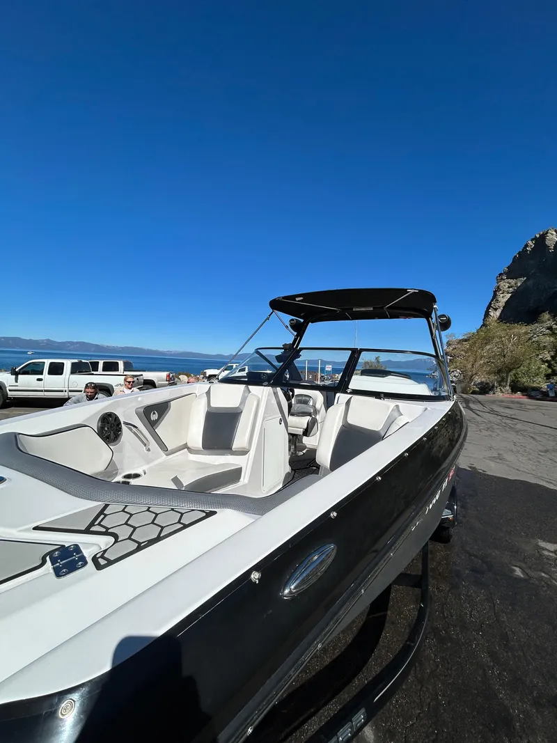 Slide: The Image of 2019 Scarab 255 ID boat parked near a scenic coastline under a clear blue sky. - 16