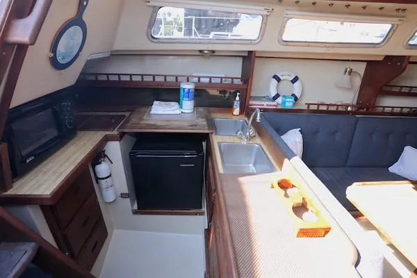 Slide: The Image of Interior of 1983 Catalina 30 sailboat with kitchenette, sink, and seating area. - 10