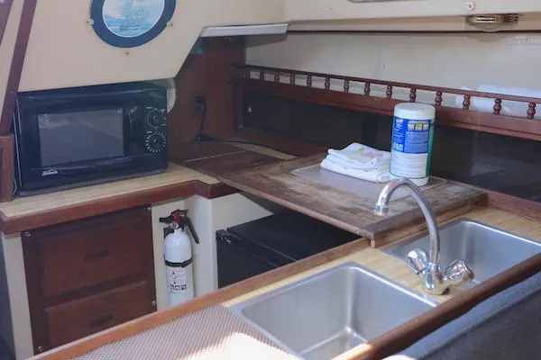 Slide: The Image of 1983 Catalina 30 yacht kitchen with sink, microwave, and wooden countertop. - 11