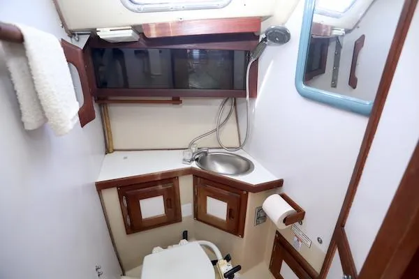 Slide: The Image of Compact bathroom in 1983 Catalina 30 sailboat with sink, mirror, and wooden cabinetry. - 15