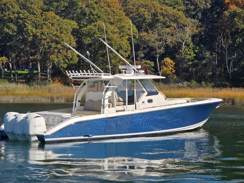 The Image of 2018 Pursuit S 408 Sport boat on calm water, surrounded by lush trees. - 0