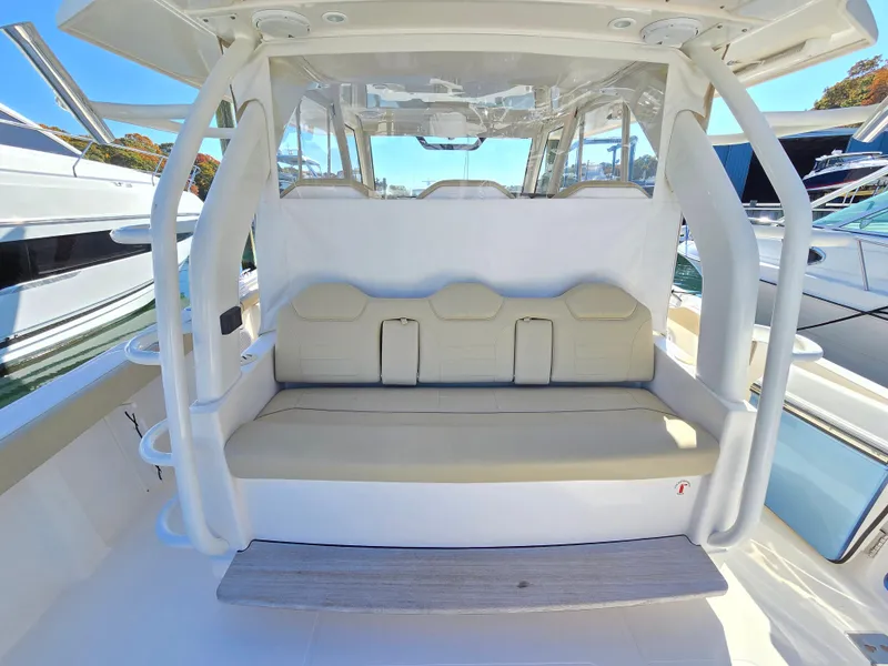 Slide: The Image of 2018 Pursuit S 408 Sport boat seating area with cushioned bench and protective canopy. - 12