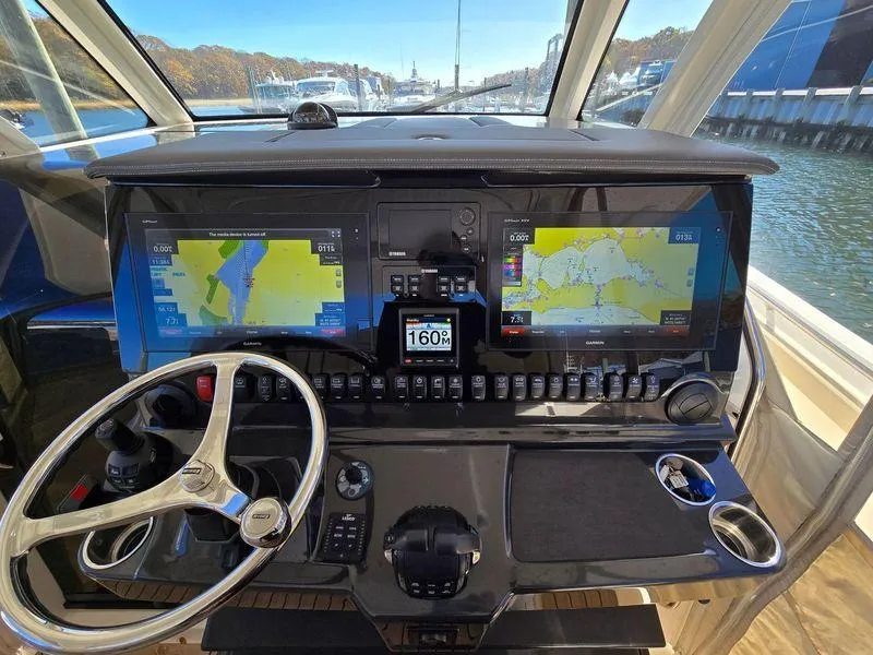 Slide: The Image of 2018 Pursuit S 408 Sport boat dashboard with dual navigation screens and steering wheel. - 18