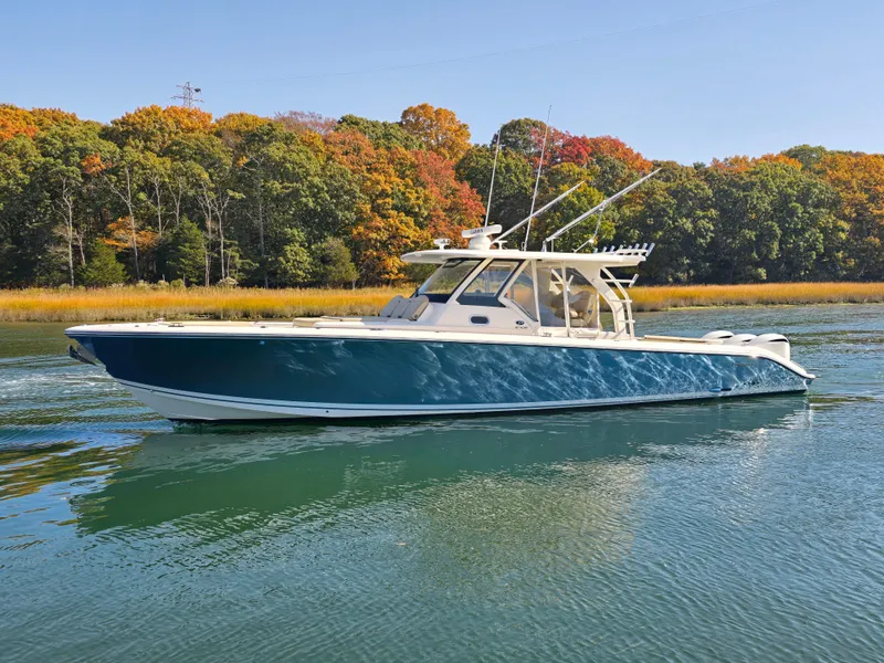 Slide: The Image of 2018 Pursuit S 408 Sport boat cruising on a serene lake with autumn foliage. - 2