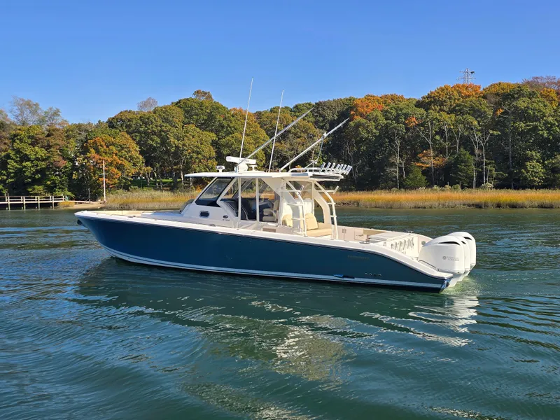 Slide: The Image of 2018 Pursuit S 408 Sport boat on calm water, surrounded by autumn trees. - 3
