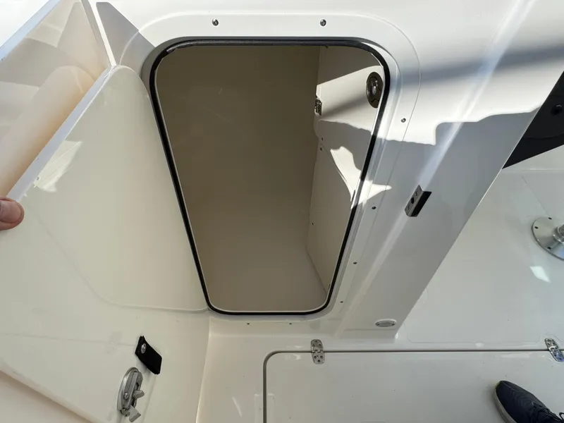 Slide: The Image of 2025 Pursuit DC 246 Dual Console boat storage compartment, open door view. - 11