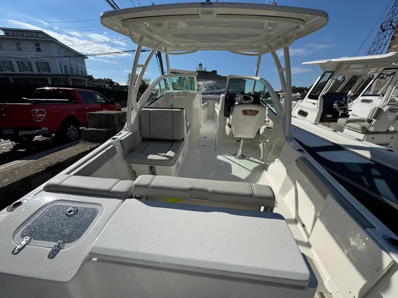 Slide: The Image of 2025 Pursuit DC 246 Dual Console boat, spacious interior, modern design, docked under clear sky. - 3