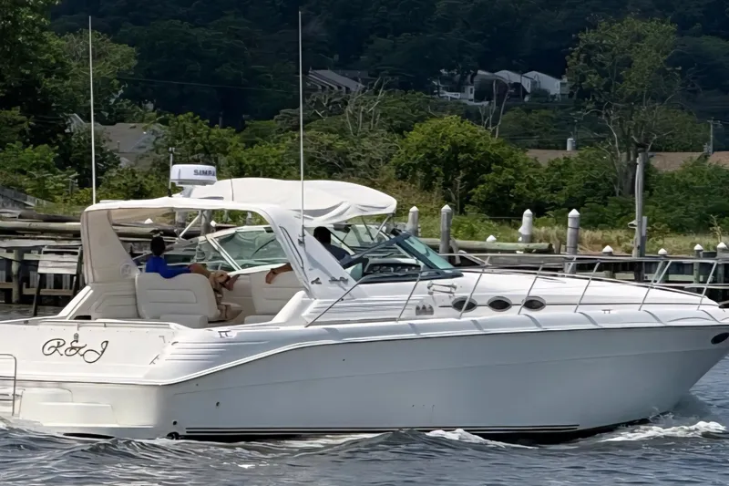 The Image of 1997 Sea Ray 400 Express Cruiser on water, with passengers, near a dock. - 0