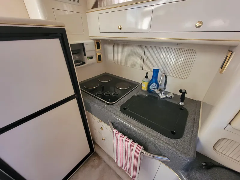 Slide: The Image of 1997 Sea Ray 400 Express Cruiser kitchen with stove, sink, and refrigerator. - 15